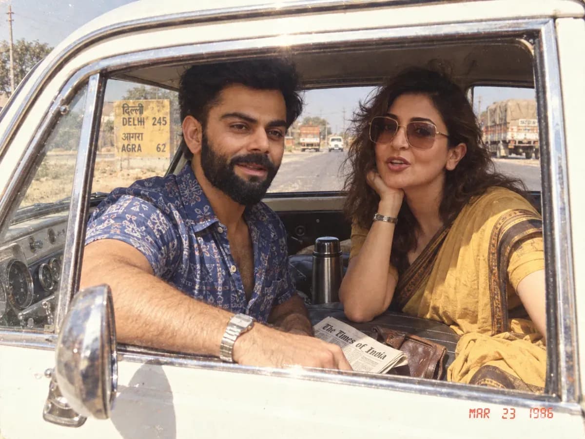 A couple seen through the wound-down window of a white Ambassador on an Indian highway in 1986, with a hard roof shadow across the opening