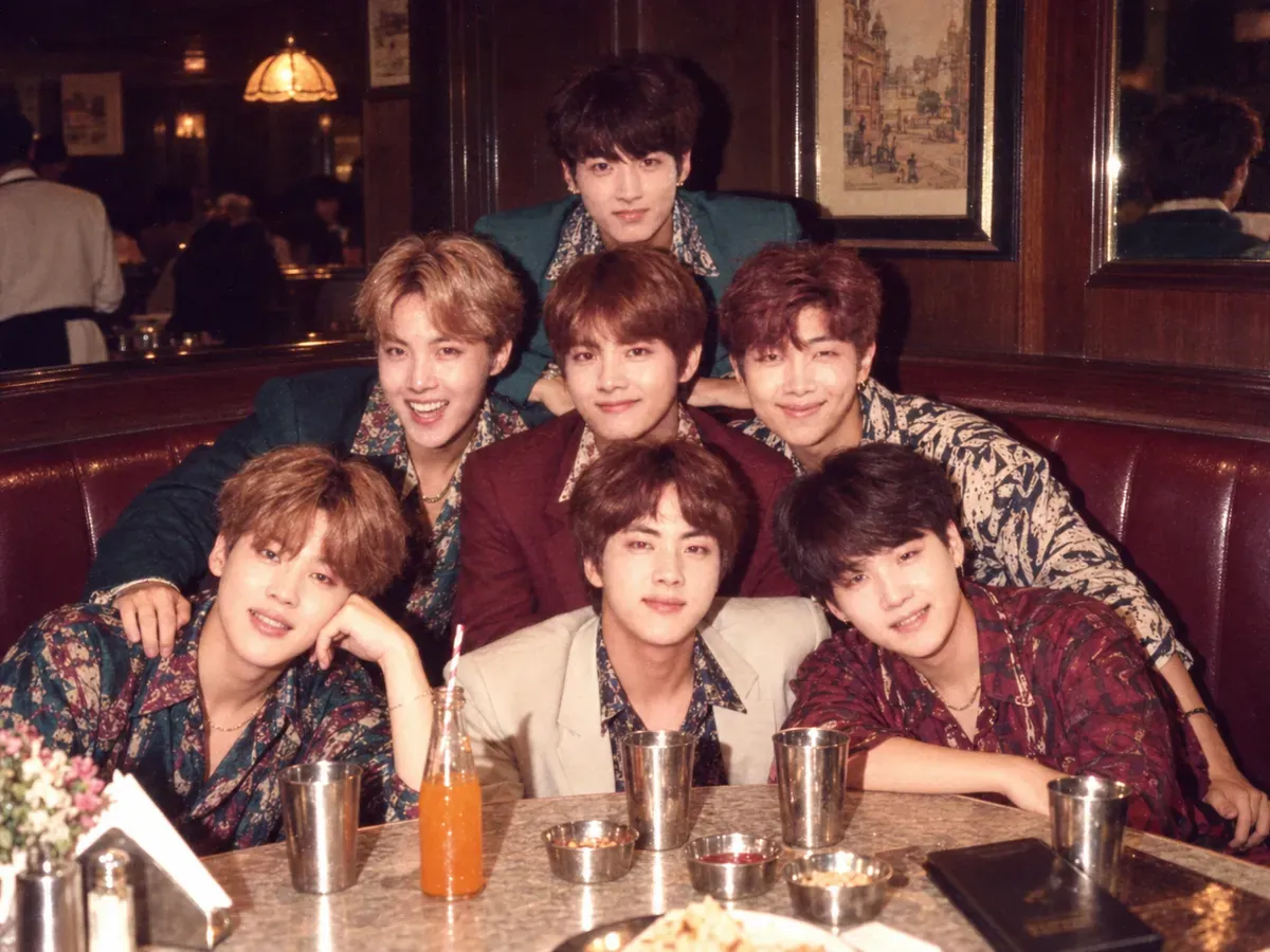 Friends squeezed into a rexine restaurant booth in 1987, lit by a hard direct flash with the nearest faces brightest