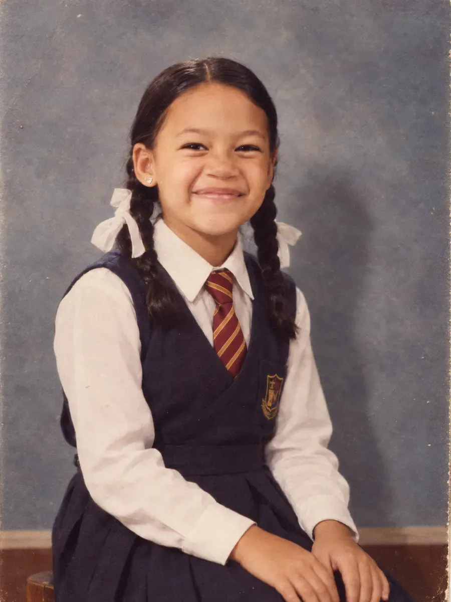 A 1985 school photo-day portrait in white shirt, striped tie and navy pullover against a grey-blue mottled canvas backdrop